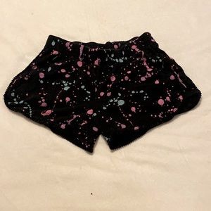 Justice black shorts with teal and pink and purple paint splatter accent